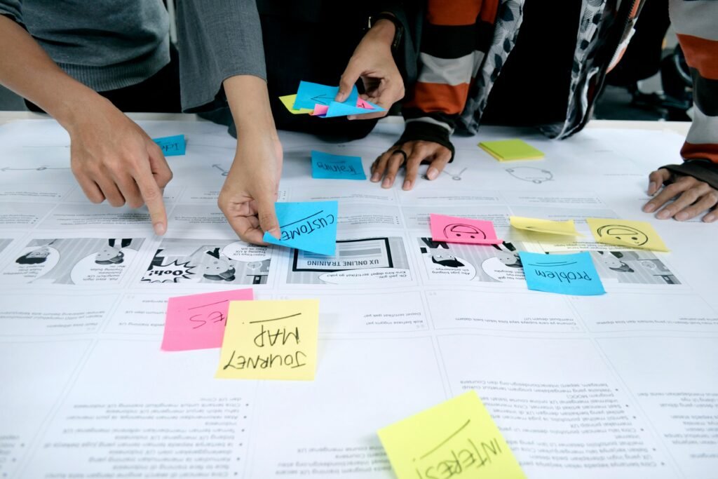 Équipe d’employés collaborant sur une Customer Journey Map (carte du parcours client) avec des post-its pour identifier étapes et émotions du parcours client. Collaborateurs travaillant sur une Customer Journey Map avec des post-its colorés pour analyser les étapes, émotions et points de douleur du parcours client et améliorer l'expérience client